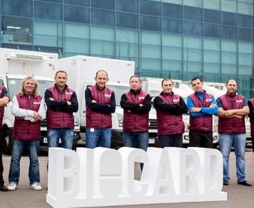 Сотрудники Biocard на фоне здания и белого логотипа. Biocard - перевозки термозависимых грузов с температурным режимом по РФ 